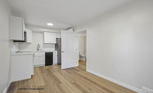 A kitchen with white cabinets and a wooden floor.
